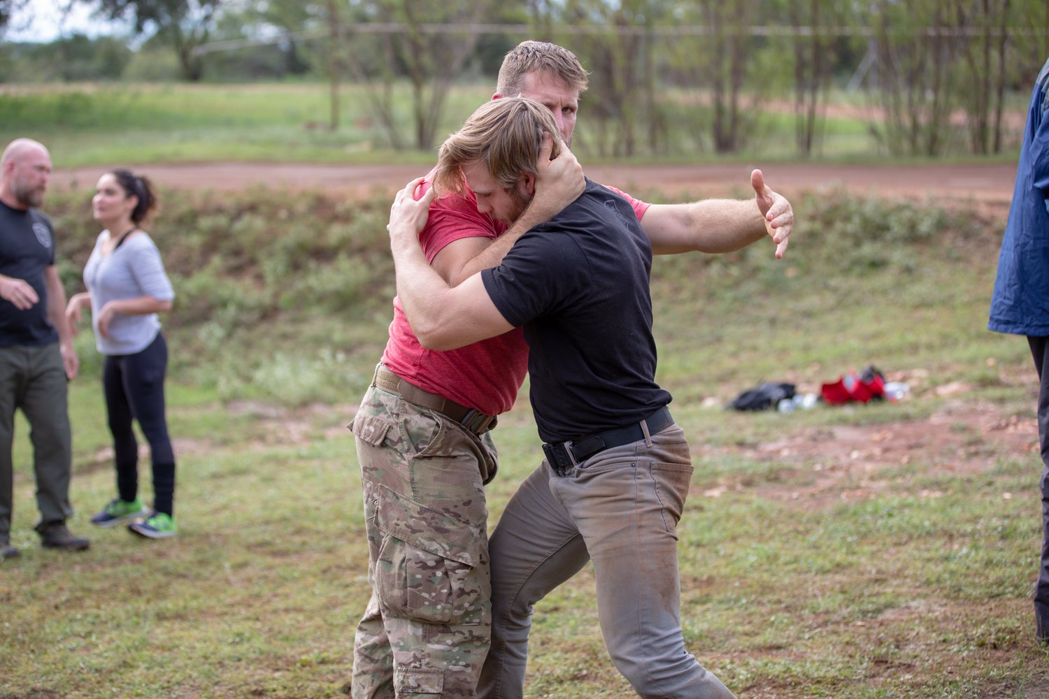 Two athletes battling for position in a collar-tie clinch during outdoor combatives training