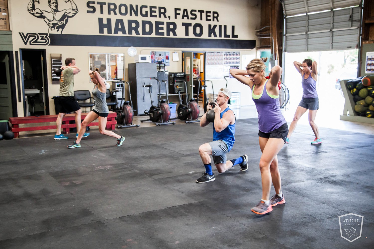 Athletes training under a gym wall that reads stronger, faster, harder to kill