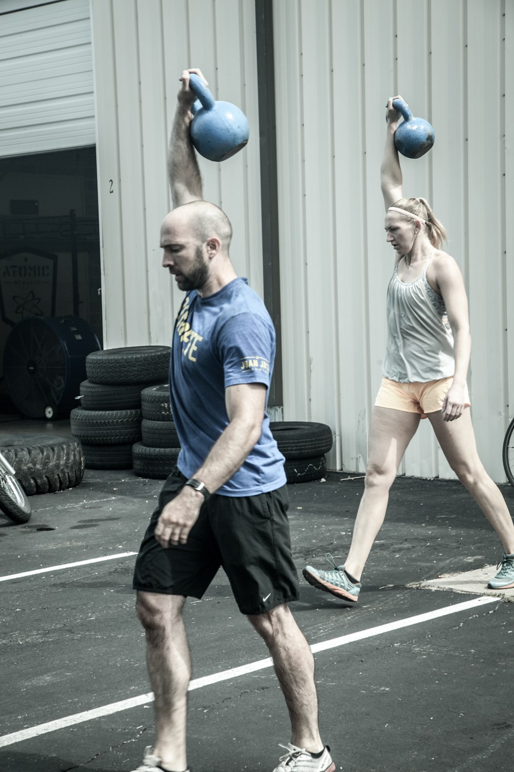 An athlete carrying two heavy kettlebells overhead, building the strength that wins grips and holds position