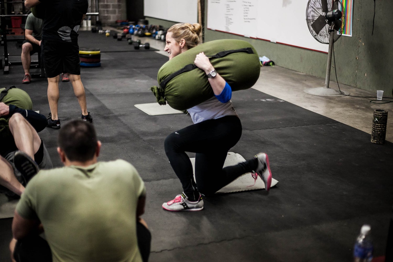 An athlete grinding a heavy sandbag through a lunge, training the mental side of hard efforts