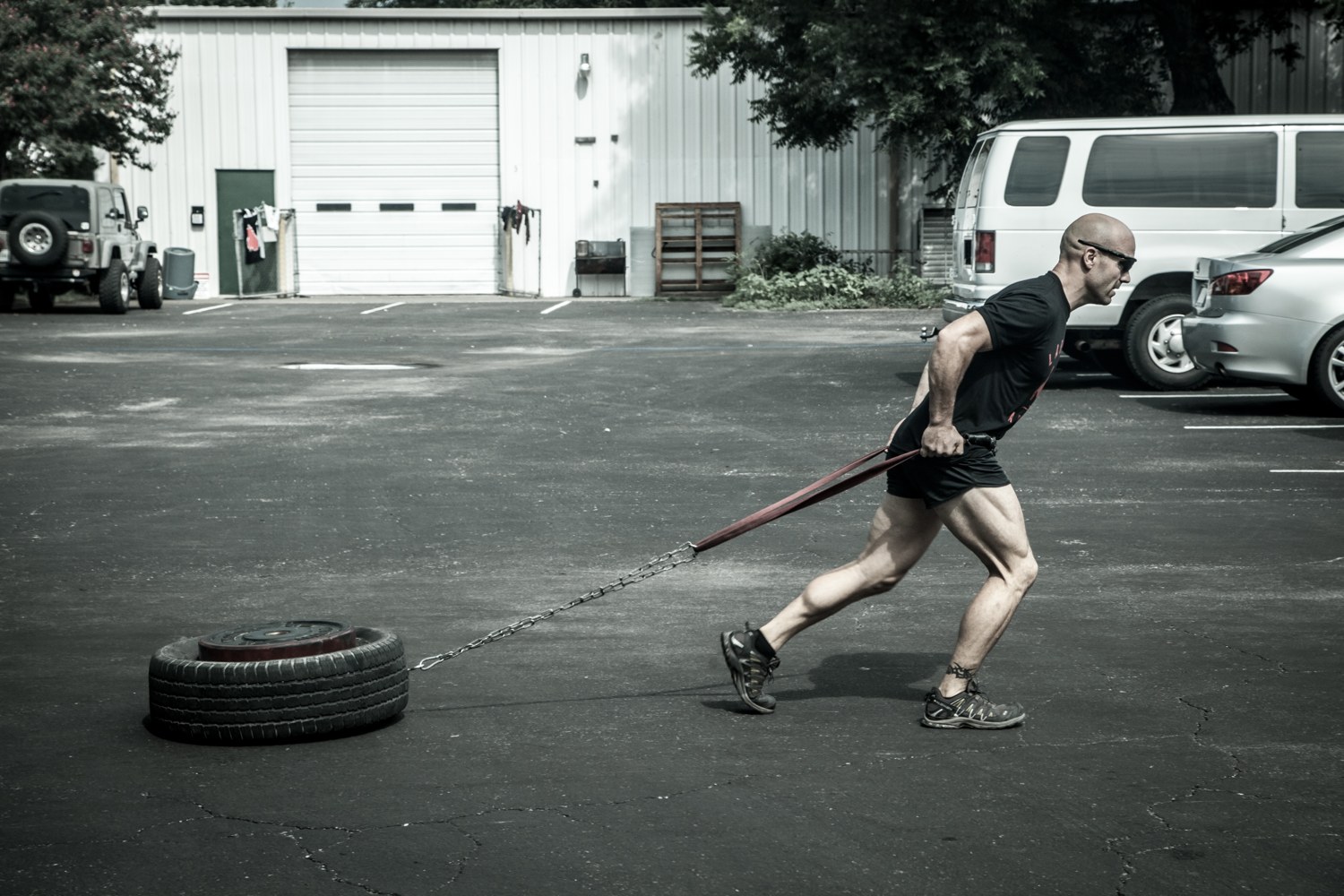 An athlete dragging a loaded sled at a hard forward lean, the strength a scramble runs on