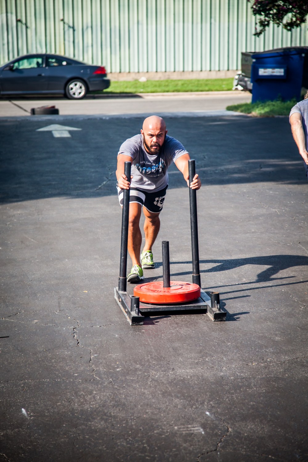 A lone athlete pushing a heavy sled, building the conditioning that holds up in the last round